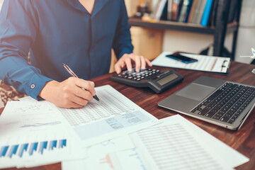 Accounting woking with data sheet on the office desk. Calculator with accounting report and financial statement on desk.