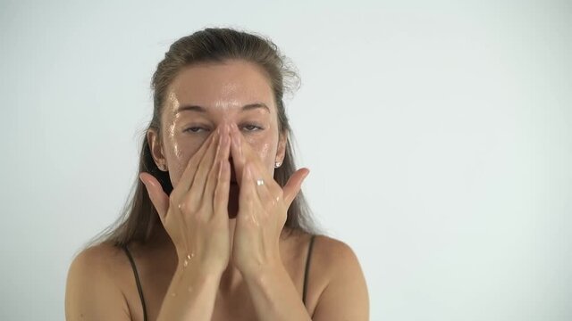 Young pretty girl applies cream to the skin of the face. Facial massage.