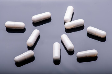 White capsules of medication on a black acrylic background