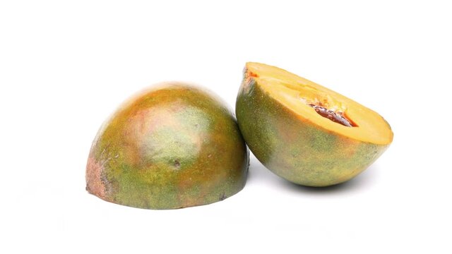 Two halves of lucuma fruit rotating on white background.
