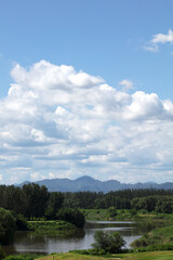 Obraz premium Green hills green water blue sky white clouds