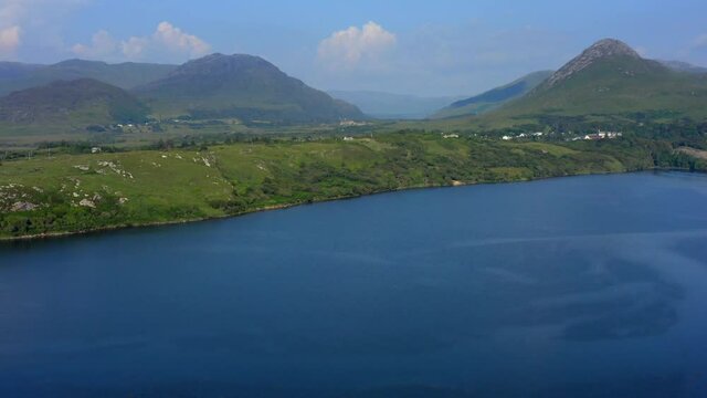 Barnaderg Bay, Letterfrack, Connemara, County Galway, Ireland, July 2021. Drone ascends, revealing view east towards Lough Bunnaboghee and Kylemore in the distance.