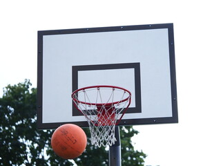Naklejka premium ball flies into the basketball hoop on the street during the game