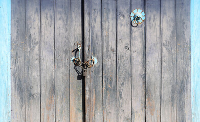 Old wooden gate closed with a padlock on a chain