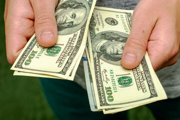 a man counts money a bundle of hundred dollar bills