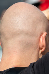 A shaved man on the back of his head. The round head of an adult male from behind.