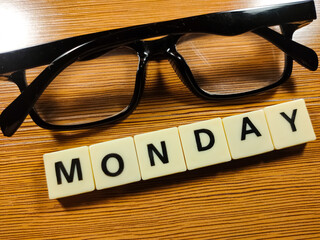 Business concept.Selective focus.Glasses and Scrabble letters with text MONDAY on wooden background.
