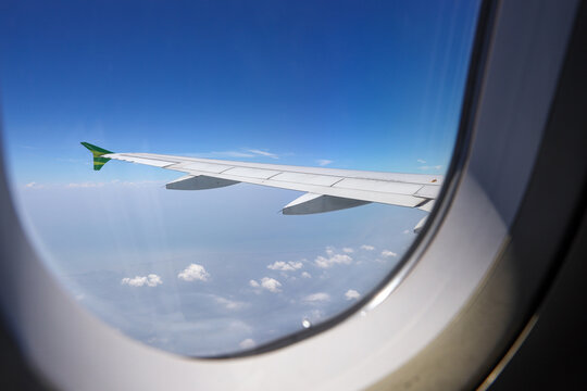 Photo of wing on blue sky through airplane window 