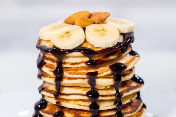 Pancakes with Chocolate Syrup, Nuts and Bananas. Stack of whole flapjack. Tasty breakfast and Healthy Food