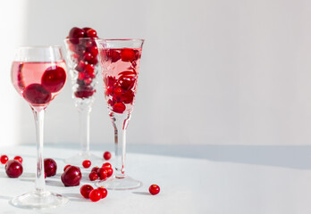 crystal glasses of pink gin or champag infused with cranberry, set of glasses of spirits drinks with berries, cherry liquor or any red alcoholic cocktail banner with space for text