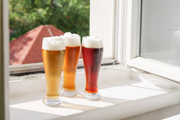 Glasses with beer on windowsill and open window at sunny day. Natural light. Oktoberfest. New...