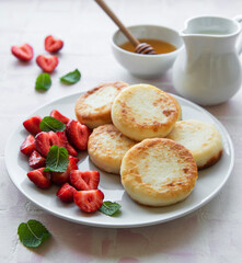 Cottage cheese pancakes, ricotta fritters on ceramic plate with  fresh strawberry.