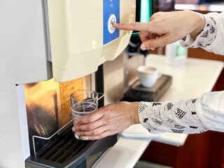 ドリンクサーバーでボタンを押す女性の指