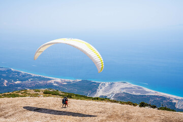 Paraglider is starting. Parachute is filling with air in the mountains alps on a sunny day in albania