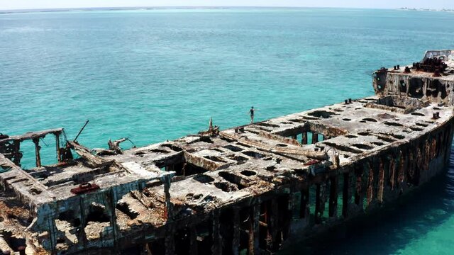 Aerial View, Lonely Female Walking on Shipwreck in Decay in Tropical Sea Water. SS Sapona, Bimini, Bahamas, Drone Shot