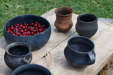 Ancient dishes on an old wooden table. Red berries in ceramic antique bowl