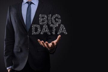 Businessman in a suit on a dark background holds the inscription BIG DATA. Storage Network Online Server Concept.Social network or business analytics representation