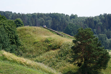 Fototapeta na wymiar Hilly country. Walking paths up the mountain. Kernavė, site of the ancient city. High hills by the river. Wooden staircase to the mountain. The famous Lithuanian landscape.
