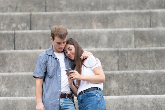 Young couple in romantic gesture looking to a smartphone. Choosing travel destination online.