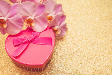 gift box in the form of heart and an orchid on a golden background