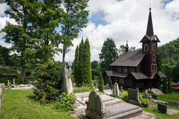 Fototapeta na wymiar Wooden church of St. Anna in Tatranska Javorina, a small town in NP Belianske Tatry, with a cemetery and trees, Slovakia