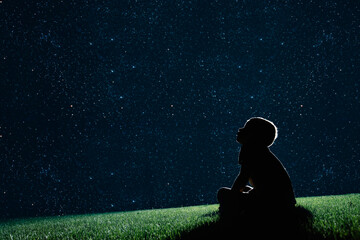 Ñchild sit on the grass at night and look at the night sky