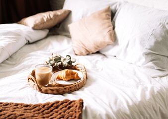 Breakfast in bed with croissant and coffee on tray