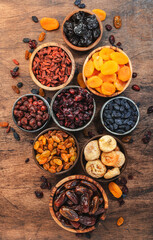 Natural Dried fruits in bowls. Healthy food snack: sun dried organic mix of apricots, figs, raisins, dates and other on wooden table, top view