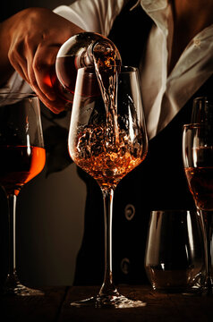 Sommelier pouring rose wine into glass at wine tasting in winery, bar or restaurant. Toned image