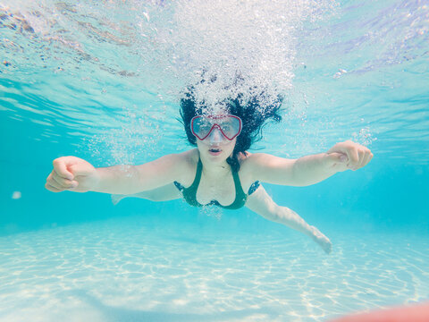 Girl with diving mask underwater in the pool