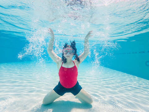 Girl with diving mask underwater in the pool