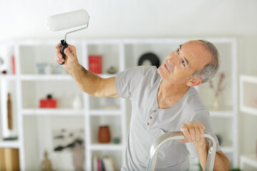 senior man painting a white wall © auremar