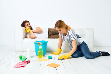 Man and woman near the sofa cleaning of the apartment light background