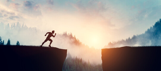 Man running up to jump between cliffs at sunset.