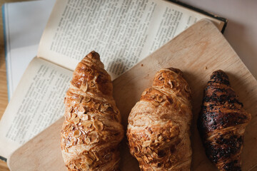 French croissants in a summer cafe on a wooden tray next to books