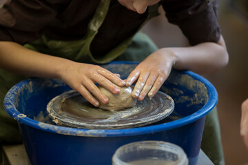 Potter's hands at work. Close-up of a potter's hands with a product on a potter's wheel. Working with clay.