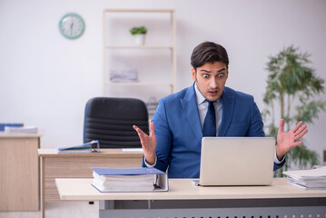 Young male employee being unhappy with excessive work