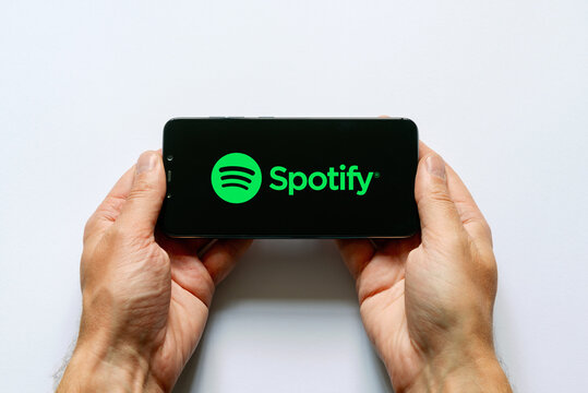 Un homme tiens dans ses mains un t&eacute;l&eacute;phone portable sur lequel il &eacute;coute des artistes sur la plateforme spotify
