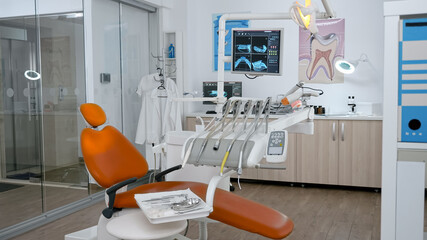 Interior of stomatology orthodontic hospital office with nobody in it ready for dental surgery equipped with modern dentistry tooth instruments. Orthodontist room with teeth xray images on display