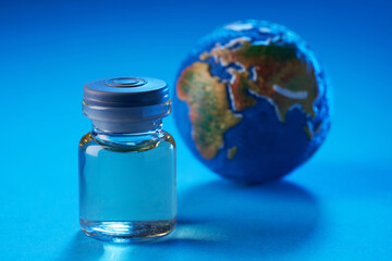 vaccine bottle and globe on blue background