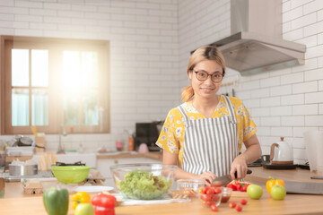 beautiful girl cooking at home preparing salad in kitchen.