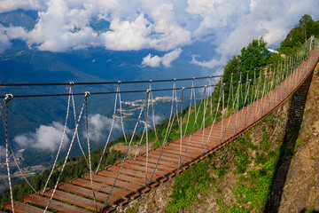Suspended wooden bridge over mountain peaks. Mountain landscape. Extreme hike at altitude. Trekking in the mountains