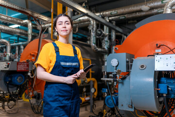 Portrait of a woman worker in a uniform and with a tablet in her hand. In the background is a...