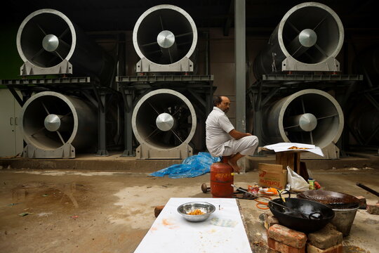 Man sits next to a newly installed "smog tower" in New Delhi