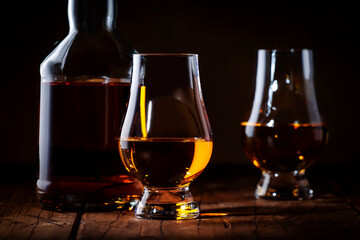 Scotch Whiskey in special glasses and bottle, old wooden background with negative space