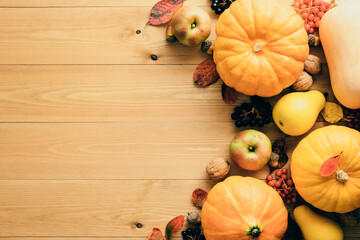 Autumn frame made of pumpkins, fallen leaves, apples, red berries, walnuts, pine cones on wooden table. Thanksgiving, Halloween, Autumn Harvest concept. Flat lay composition, top view, copy space.