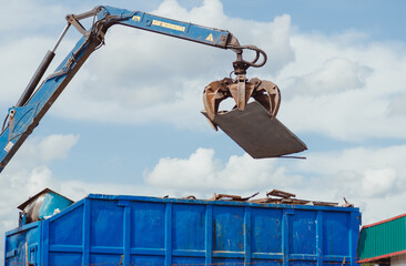 Crane-loading scrap grabber old metal at industrial metal recycling plant
