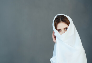 pretty woman covers herself with white cloth with head makeup fashion studio