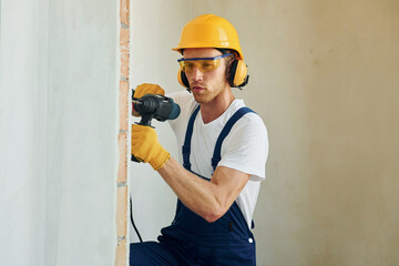 Professional service. Young man working in uniform at construction at daytime