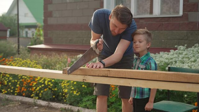 Male carpenter with his son working outside near the house